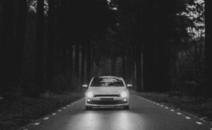 A car passes through a road in the middle of a wooded forest. Photo by Jorgen Hendriksen on Unsplash.