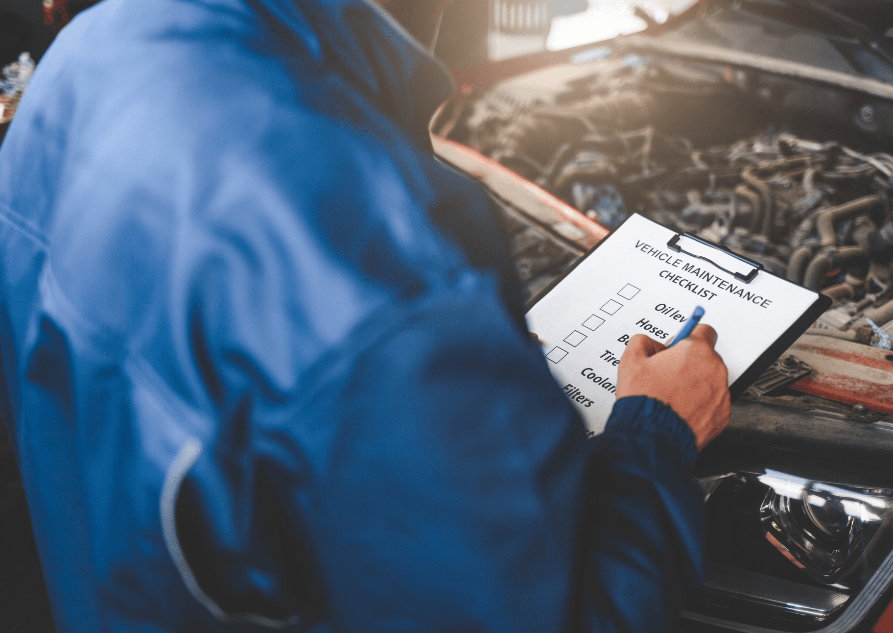 A person in a blue jacket regularly checks the car engine for optimal performance.