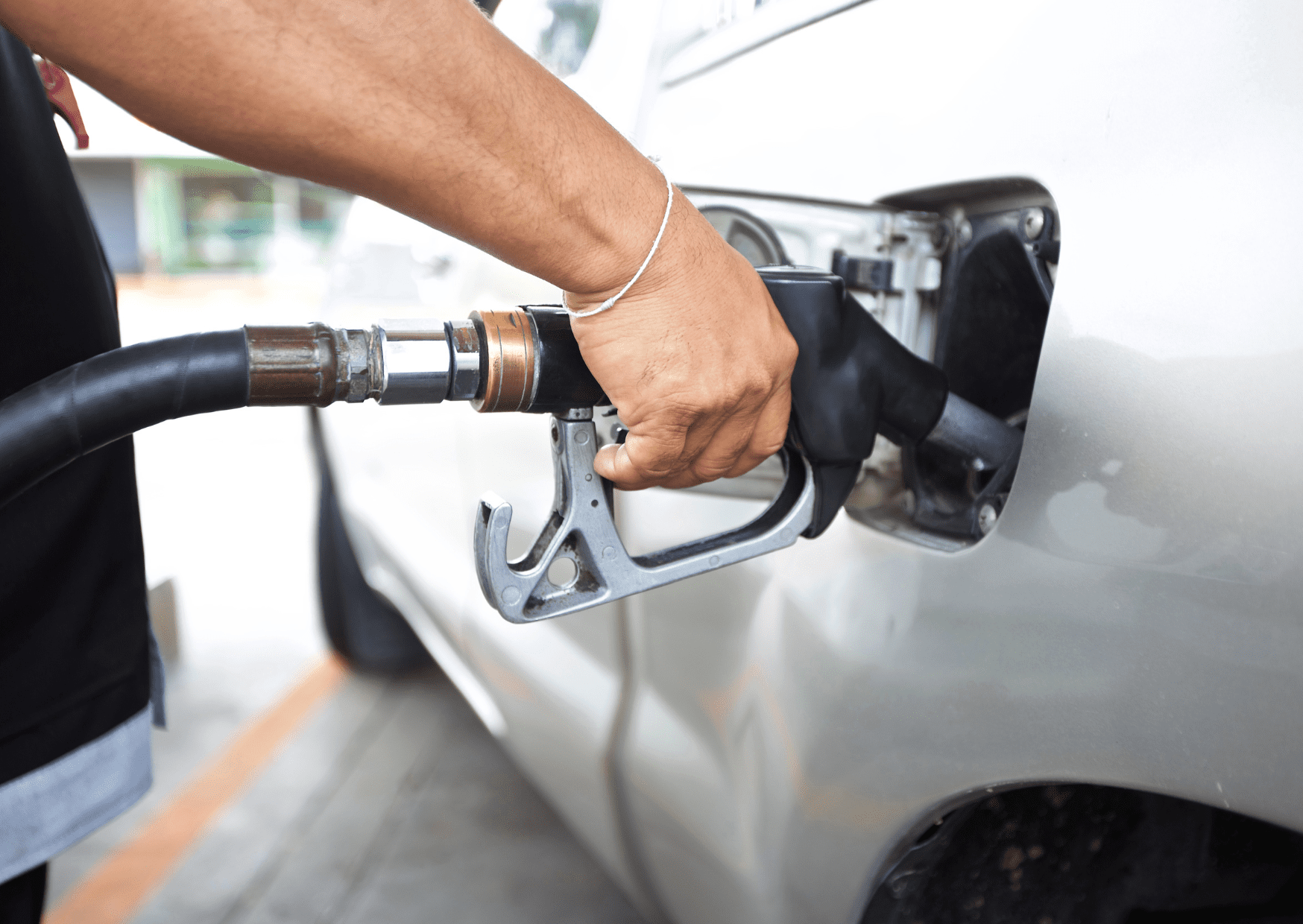 A persone fueling up the white vehicle.