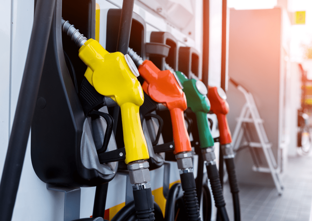 Close-up of fuel pump nozzles in yellow, orange, and green at a gas station, ready for refueling vehicles.