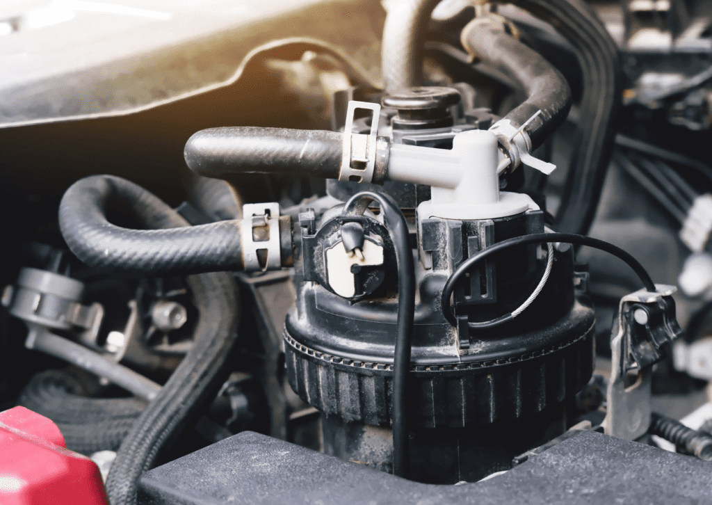 Close-up of a car engine fuel system with hoses, clamps, and connectors showing mechanical components.