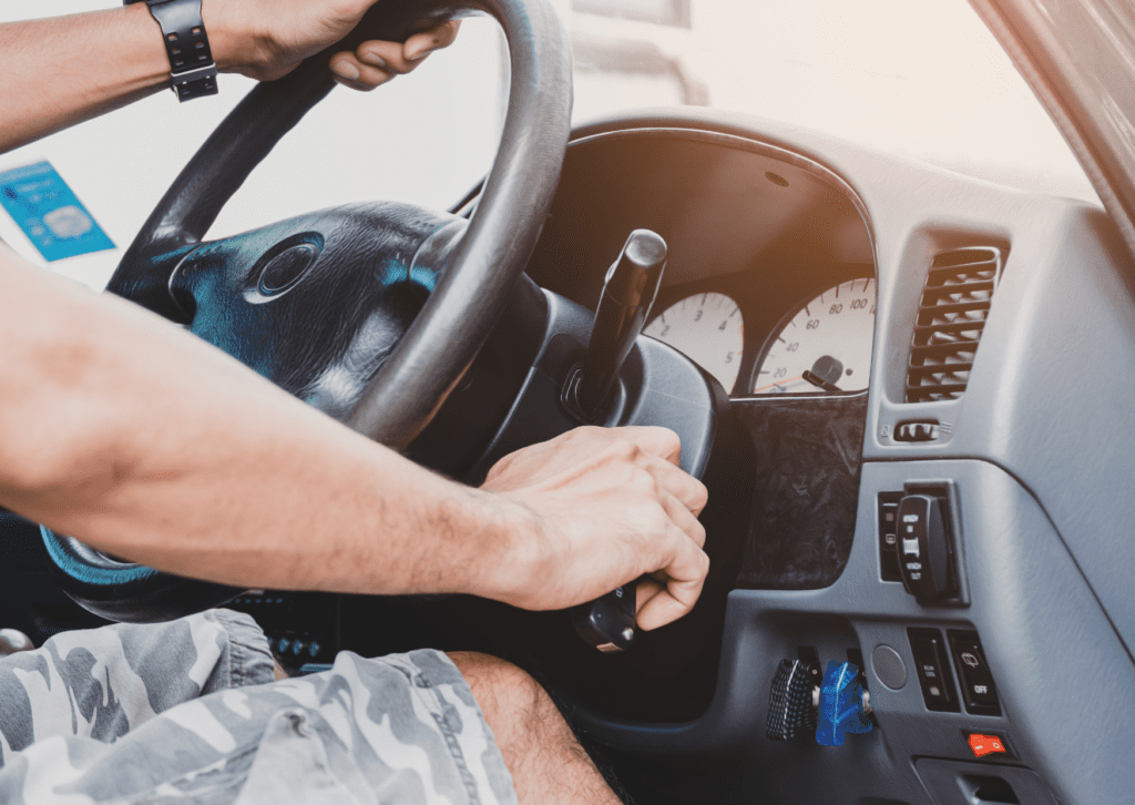 Person turning a car key in the ignition while holding the steering wheel, attempting to start the vehicle.