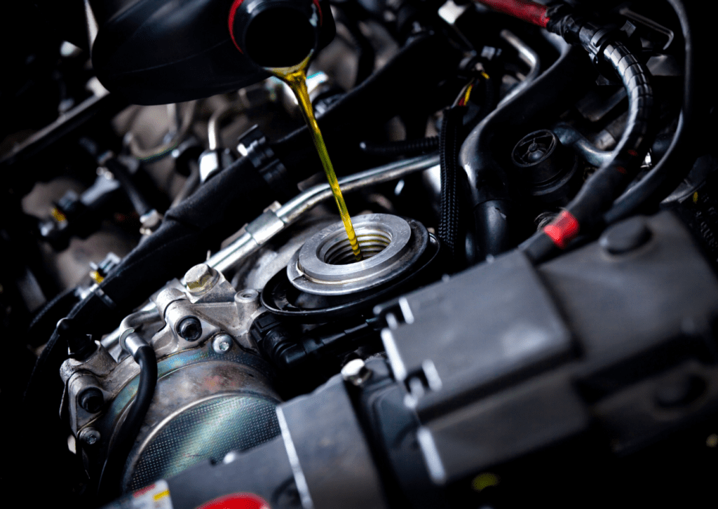 Golden engine oil being poured into a car engine, highlighting vehicle maintenance and lubrication.