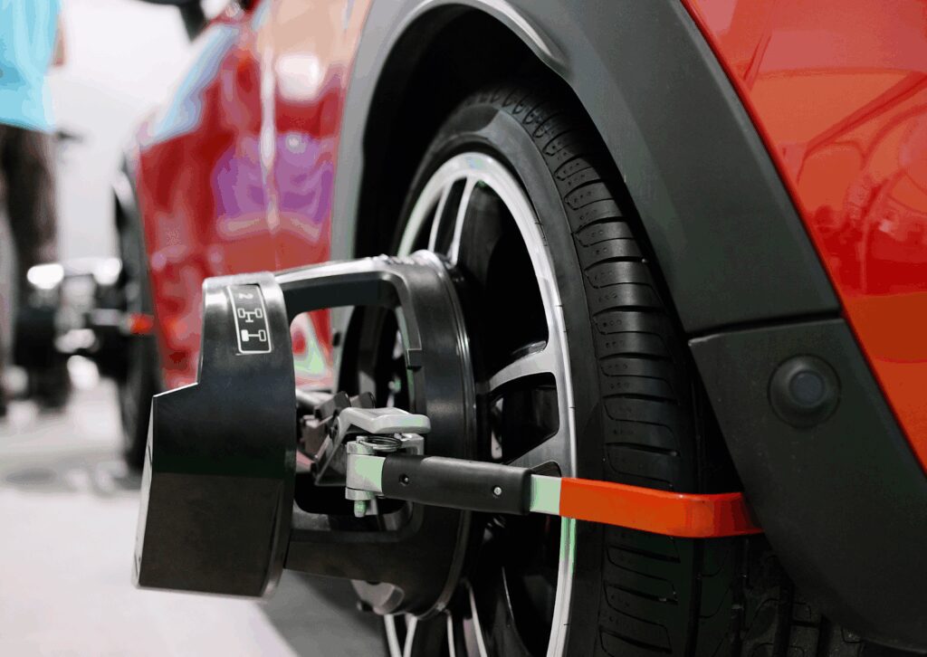 Close-up of wheel alignment sensor mounted on red vehicle's tire during precision alignment service.