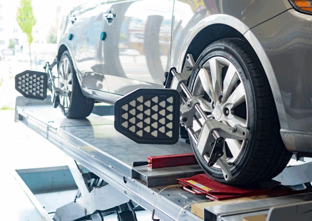 Car on lift with sensors and reflectors mounted on wheels during a computerized wheel alignment check.