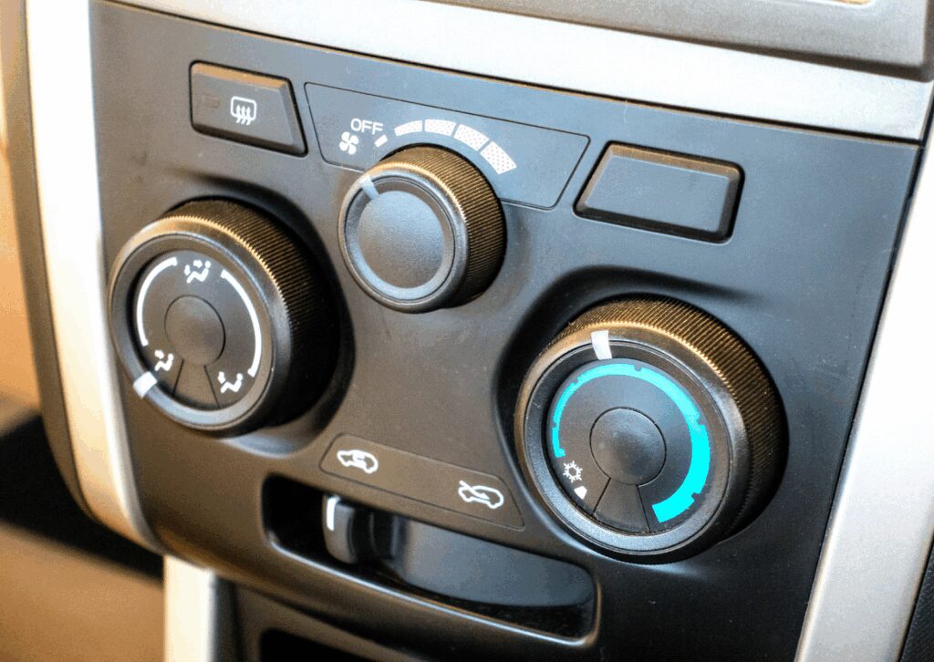 Vehicle dashboard showing air flow, fan speed, and temperature knobs for climate adjustment.