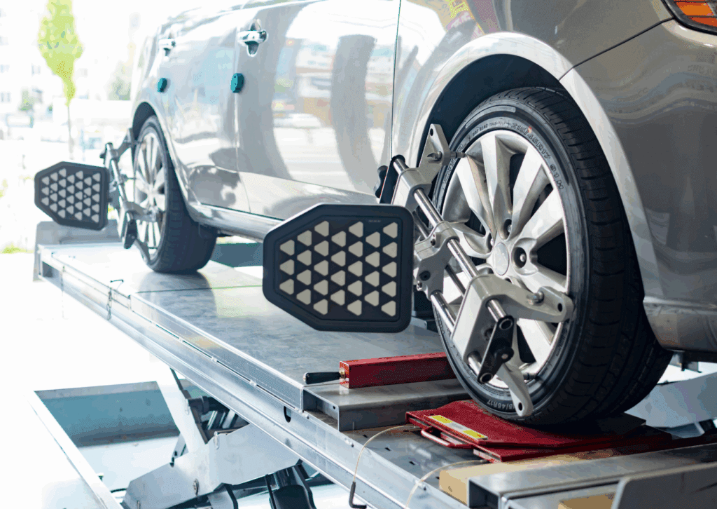 Modern car on lift undergoing 4 wheel alignment with digital sensors attached to all four wheels.