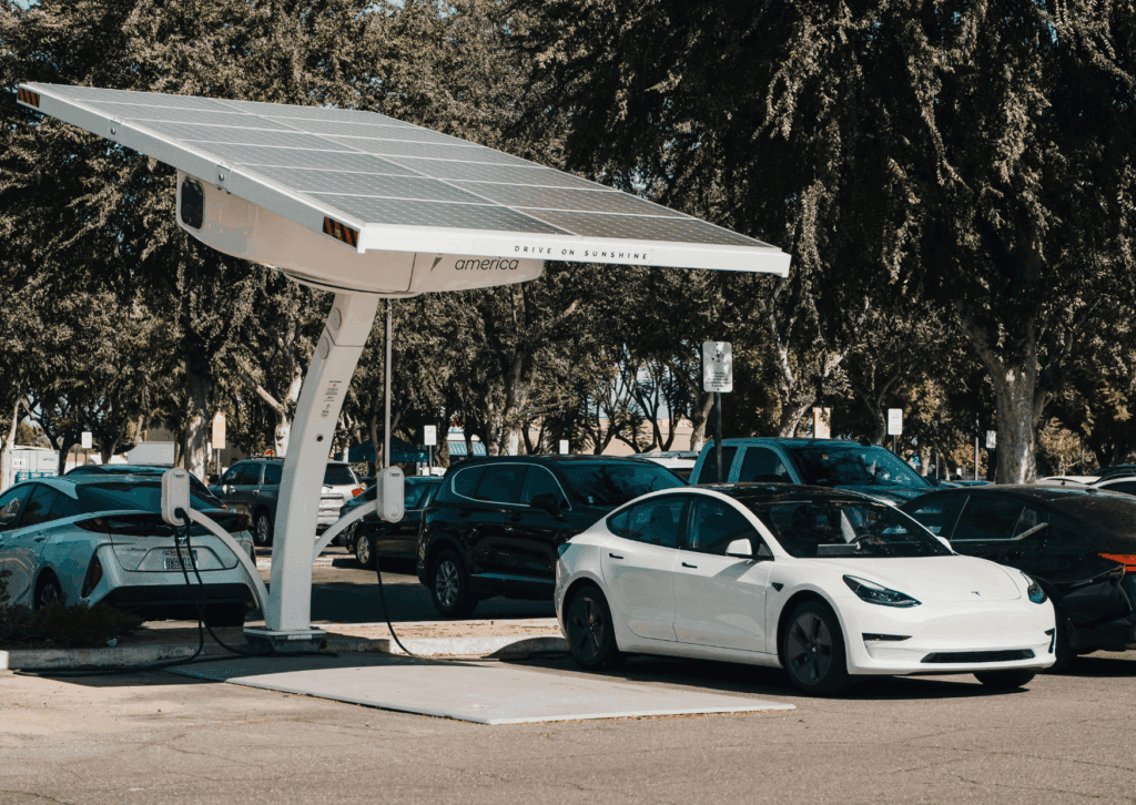 Tesla charging at solar-powered station, highlighting importance of electric vehicle maintenance schedule.