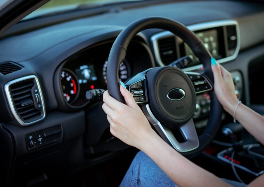 Driver hands grip steering wheel inside modern car cabin, highlighting steering and suspension repair warning signs.