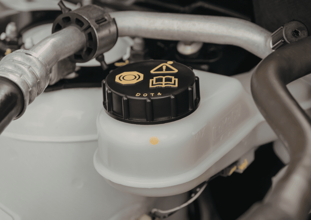 Technician uses laptop for car diagnostics on open engine bay in workshop, with engine tuning graph overlay.