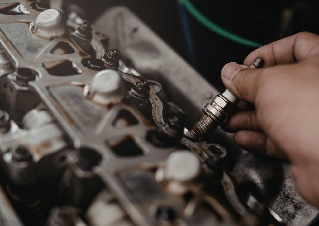 Close-up of hand changing spark plug in engine, showing detailed repair work inside cylinder head.