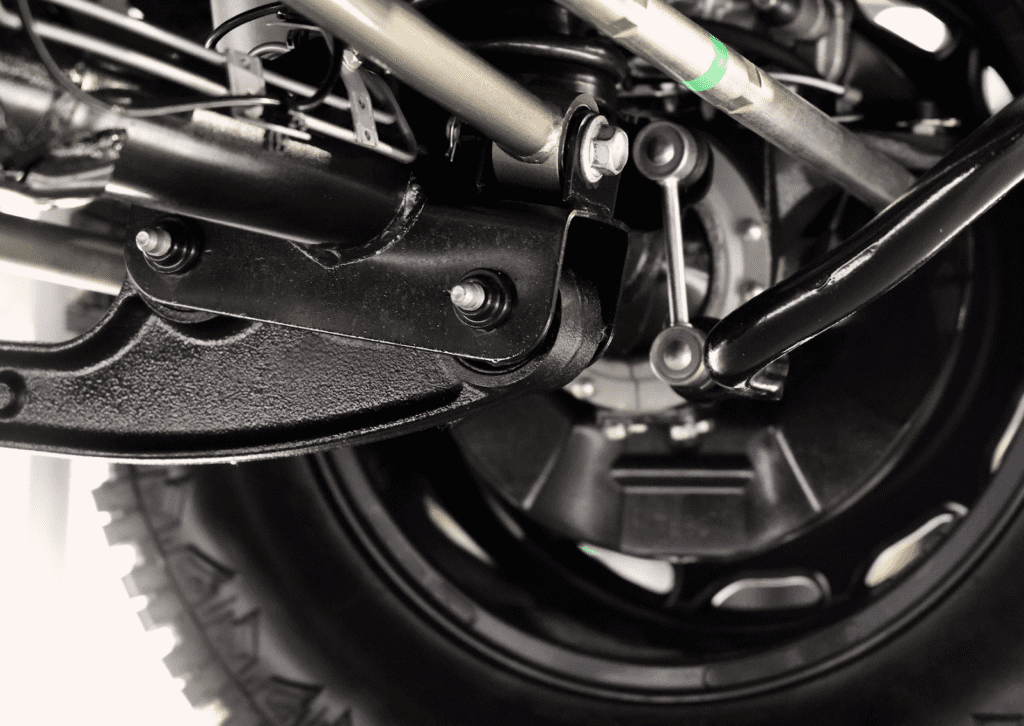 Close-up of vehicle suspension arm, wheel hub, and linkage components during inspection.