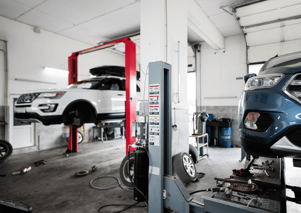 Bright auto repair shop with SUVs on lifts, service bay tools, and active vehicle maintenance.