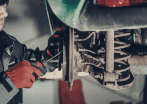 Mechanic inspecting wheel hub and spring while asking what are the 3 common suspension noises today