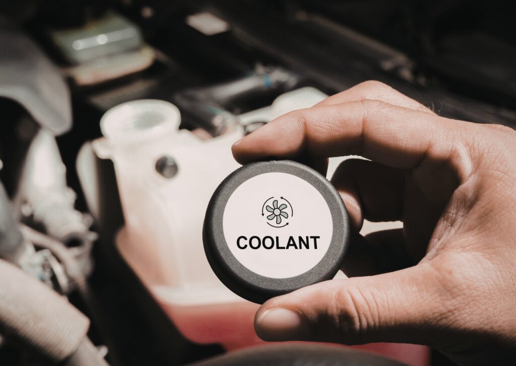 Hand holding coolant cap over engine bay for types-of-car-leaks inspection and fluid level check.