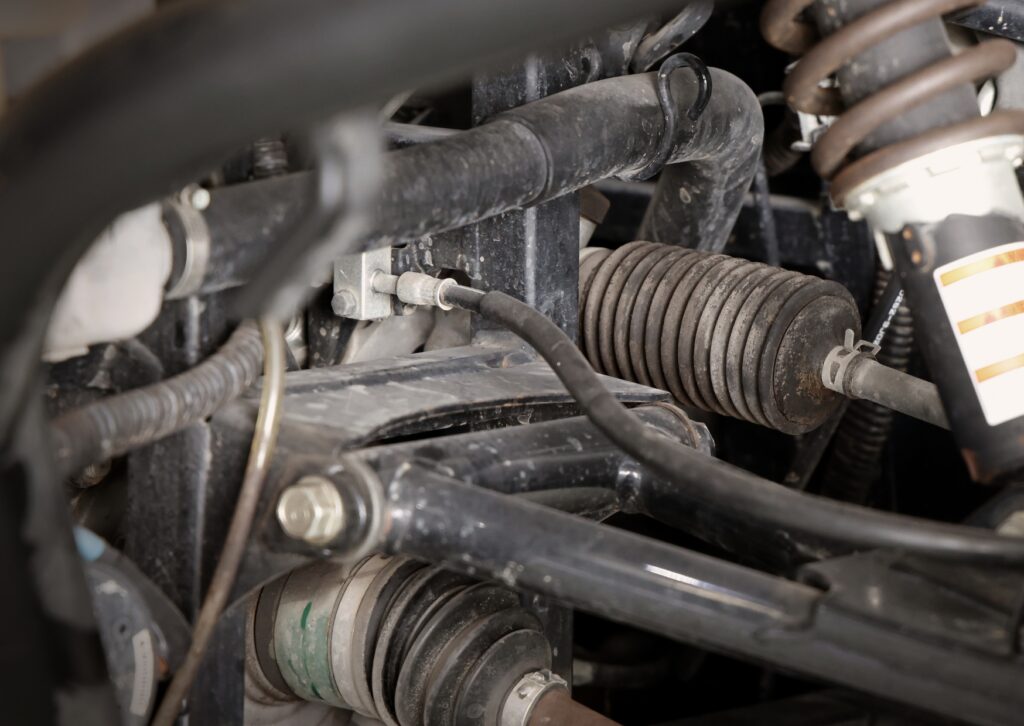 Close-up of steering and suspension linkage inside wheel well, highlighting worn components clearly.