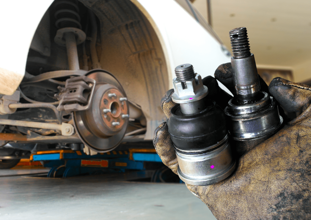 Mechanic holds worn ball joints by lifted wheel to diagnose car clunking noise in suspension 