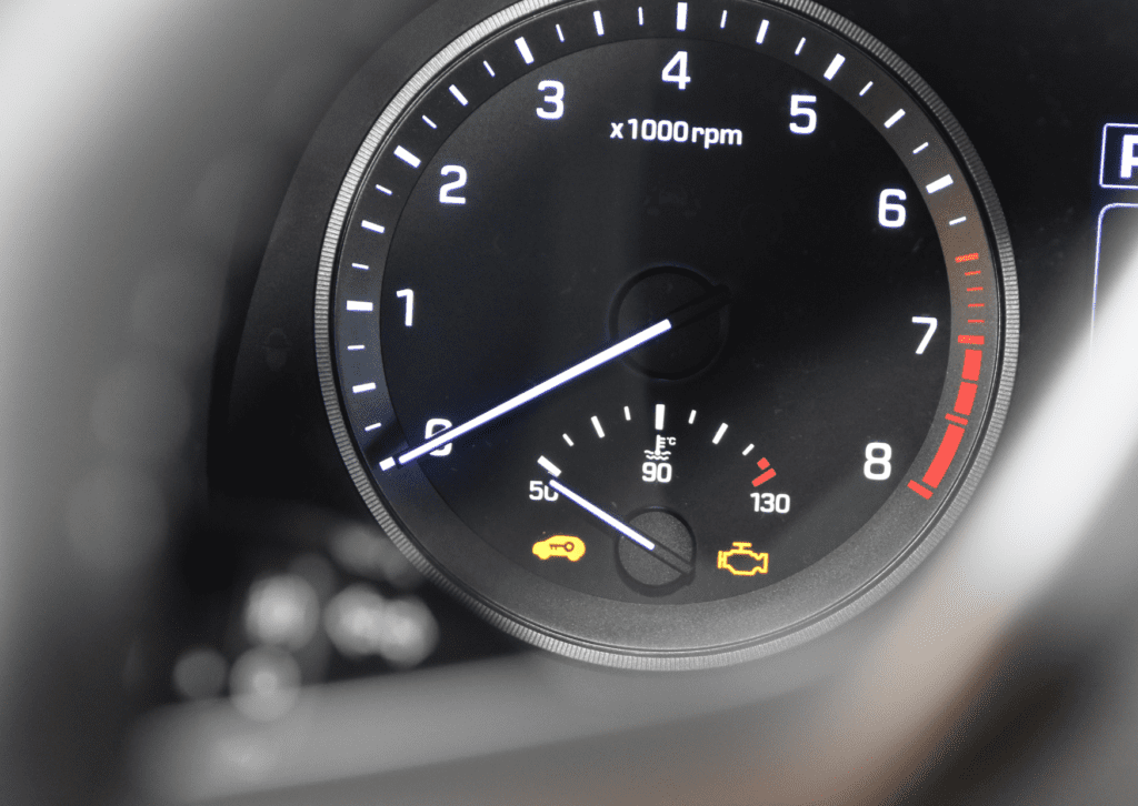 Dashboard tachometer with key and flashing check engine light vs solid warning icons illuminated 