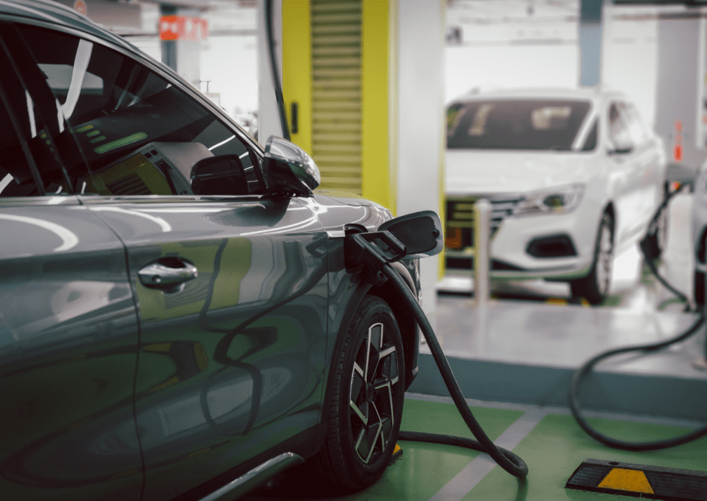 Electric vehicle charging at indoor station with another car plugged in behind it for service 