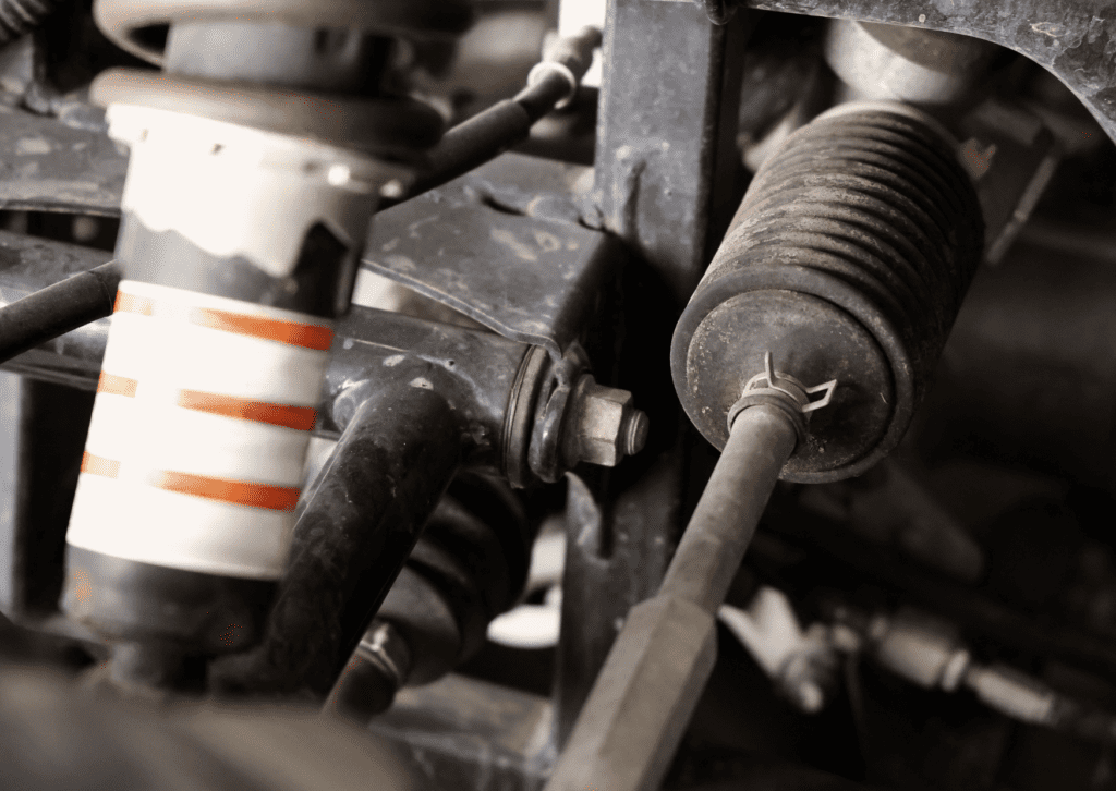 Close-up of vehicle suspension linkage, shock, and steering components under the chassis area 