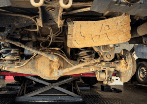 Rusty rear suspension and axle components showing suspension-noises-in-car under a lifted truck 