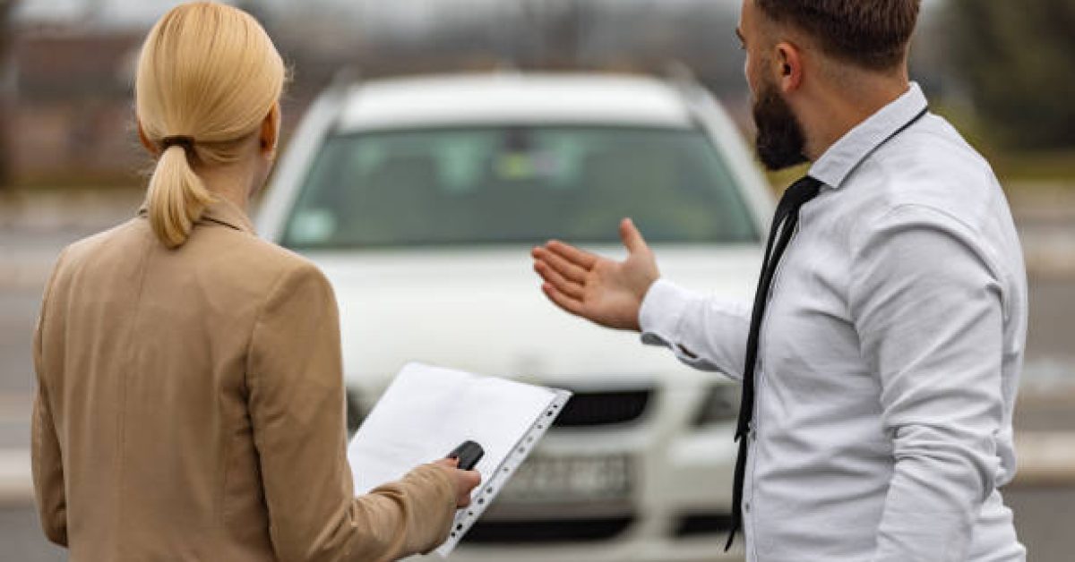 Young man and woman in a car rental service standing while looking at car.