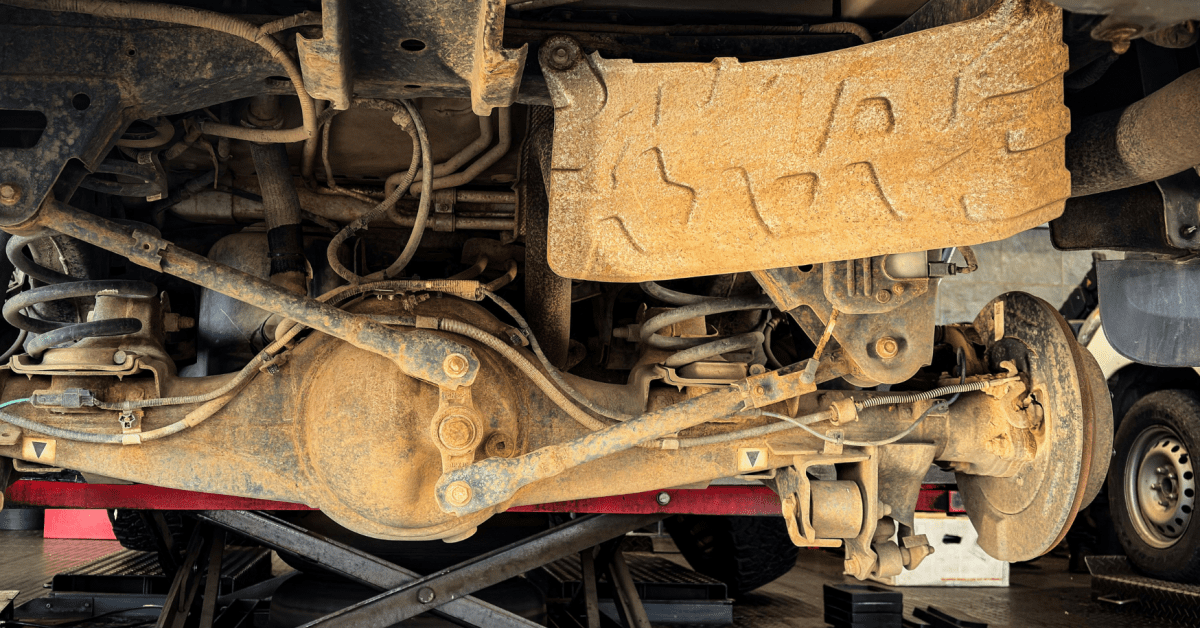 Rusty rear suspension and axle components showing suspension-noises-in-car under a lifted truck 