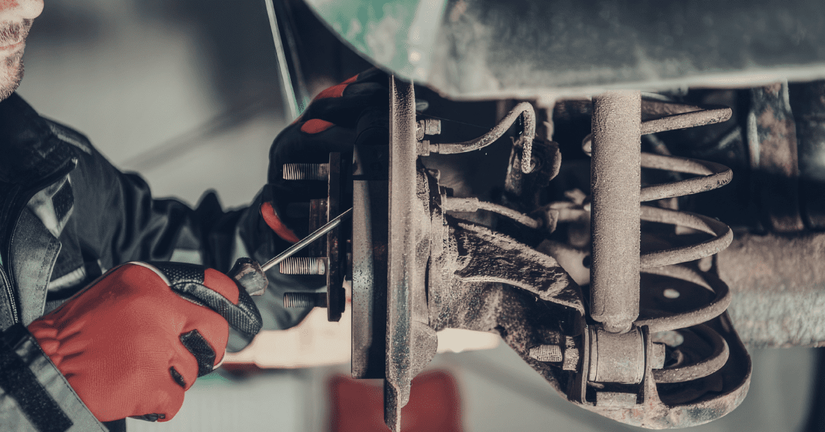 Mechanic inspecting wheel hub and spring while asking what are the 3 common suspension noises today