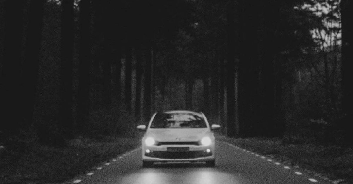 A car passes through a road in the middle of a wooded forest. Photo by Jorgen Hendriksen on Unsplash.