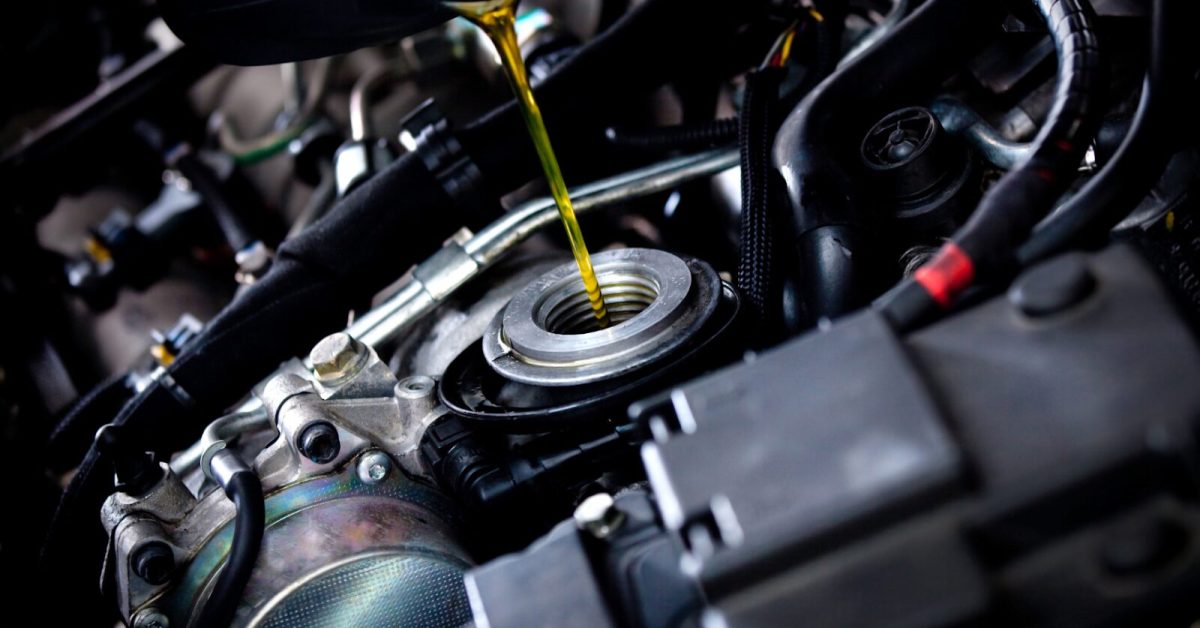 kms between oil changes Motor oil being poured into engine during service, highlighting maintenance and how many kms between oil changes.